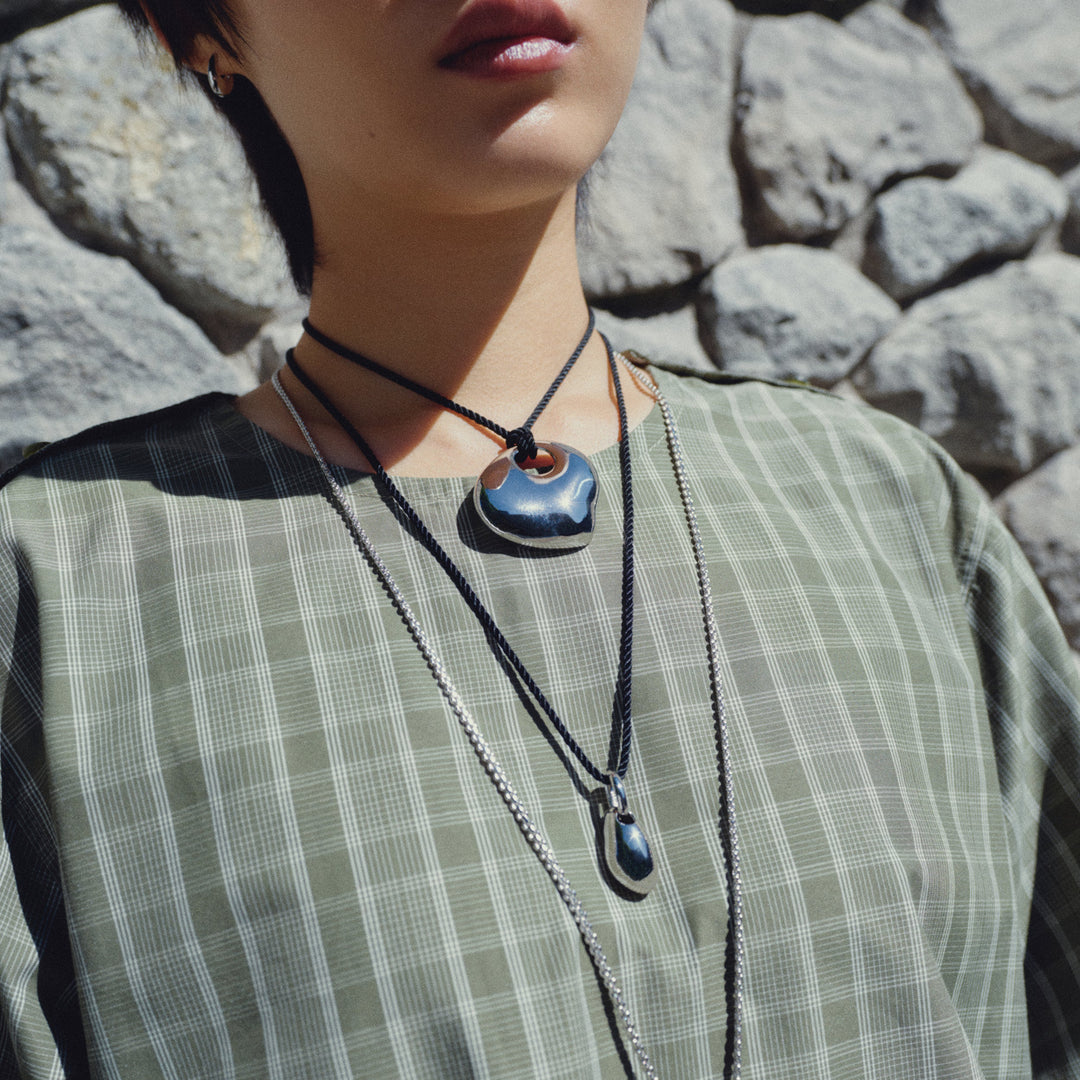 Layered pendant necklaces with blue stone and silver accents worn over striped shirt
