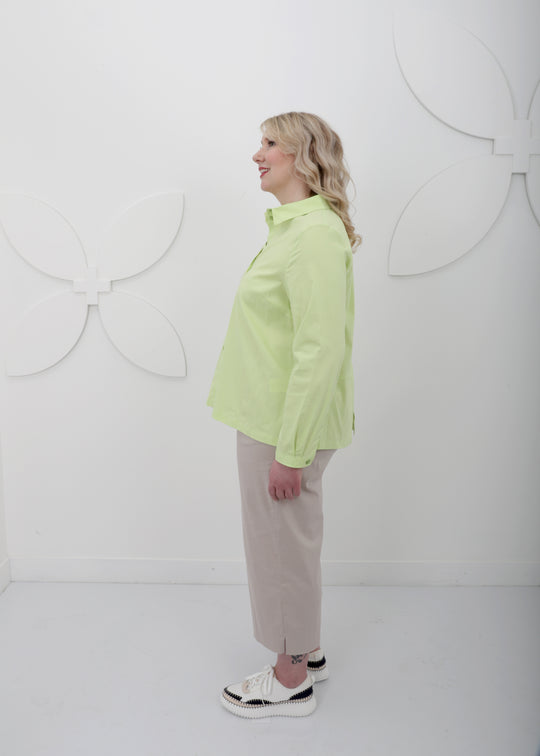 Side view of Toni T. plus size long sleeve A-line shirt in stretch poplin, bamboo green color on model with linen ankle pant