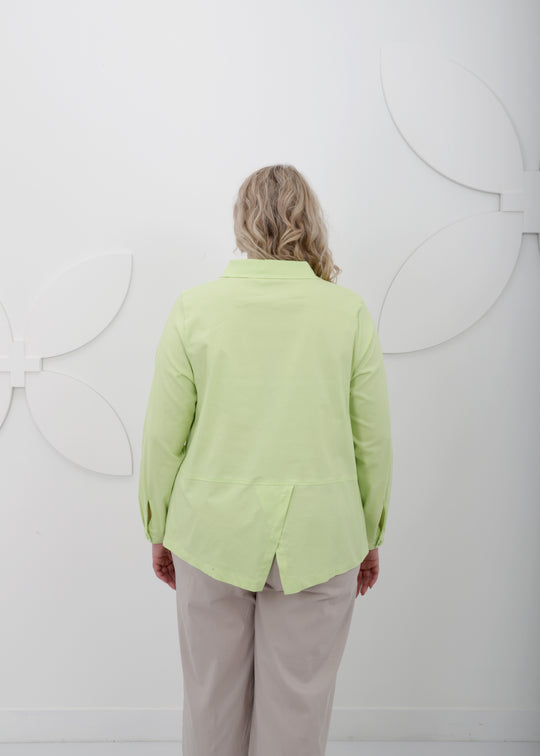 back view of Toni T. plus size long sleeve A-line shirt in stretch poplin, bamboo green color on model with linen ankle pant