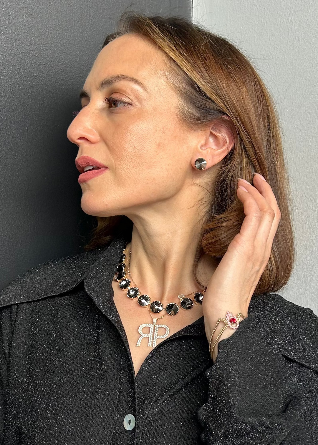 Model wearing a crystal rivoli statement necklace with dark smoky stones in gold setting, side profile view