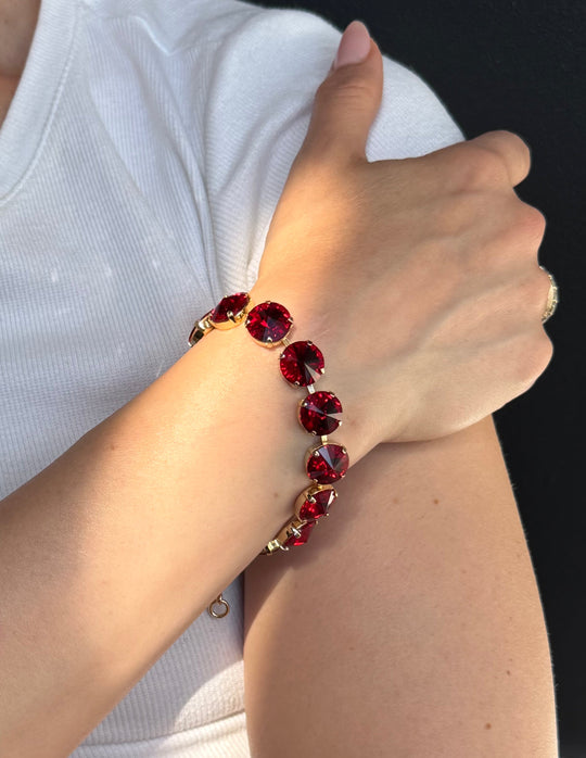 Round red crystal rivoli bracelet in gold prong settings worn on a wrist