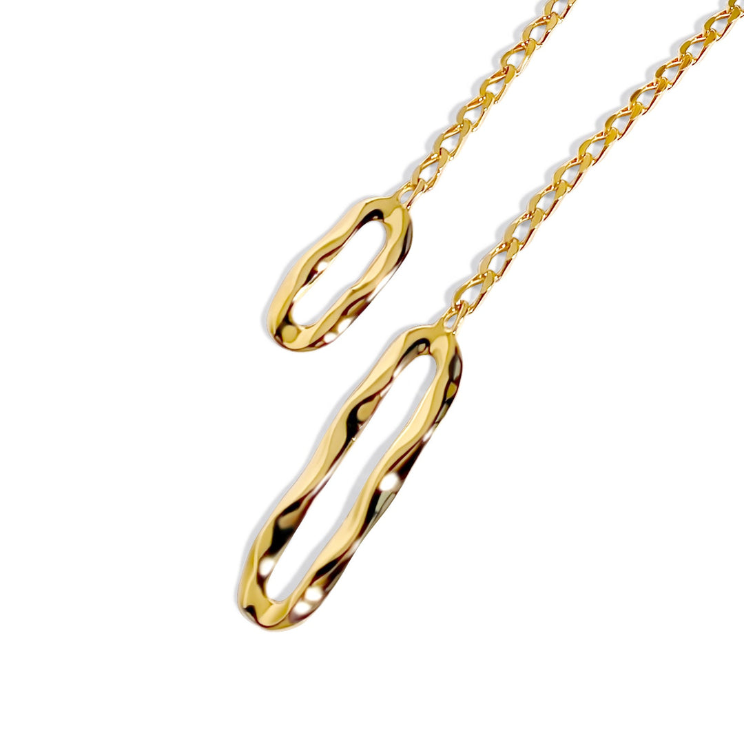 Gold lariat necklace with elongated oval links on chain against white background
