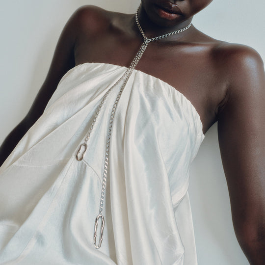 Chain lariat necklace with oval links worn by model in white strapless top