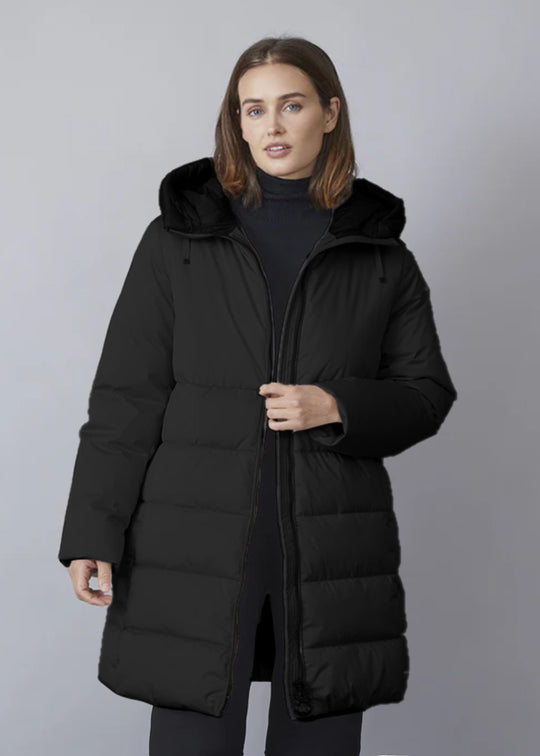 A woman wearing a black hooded quilted puffer jacket with a stand-up collar, zipper closure, and a spacious hood. The jacket has pockets with zippers and a inner pocket with zipper.