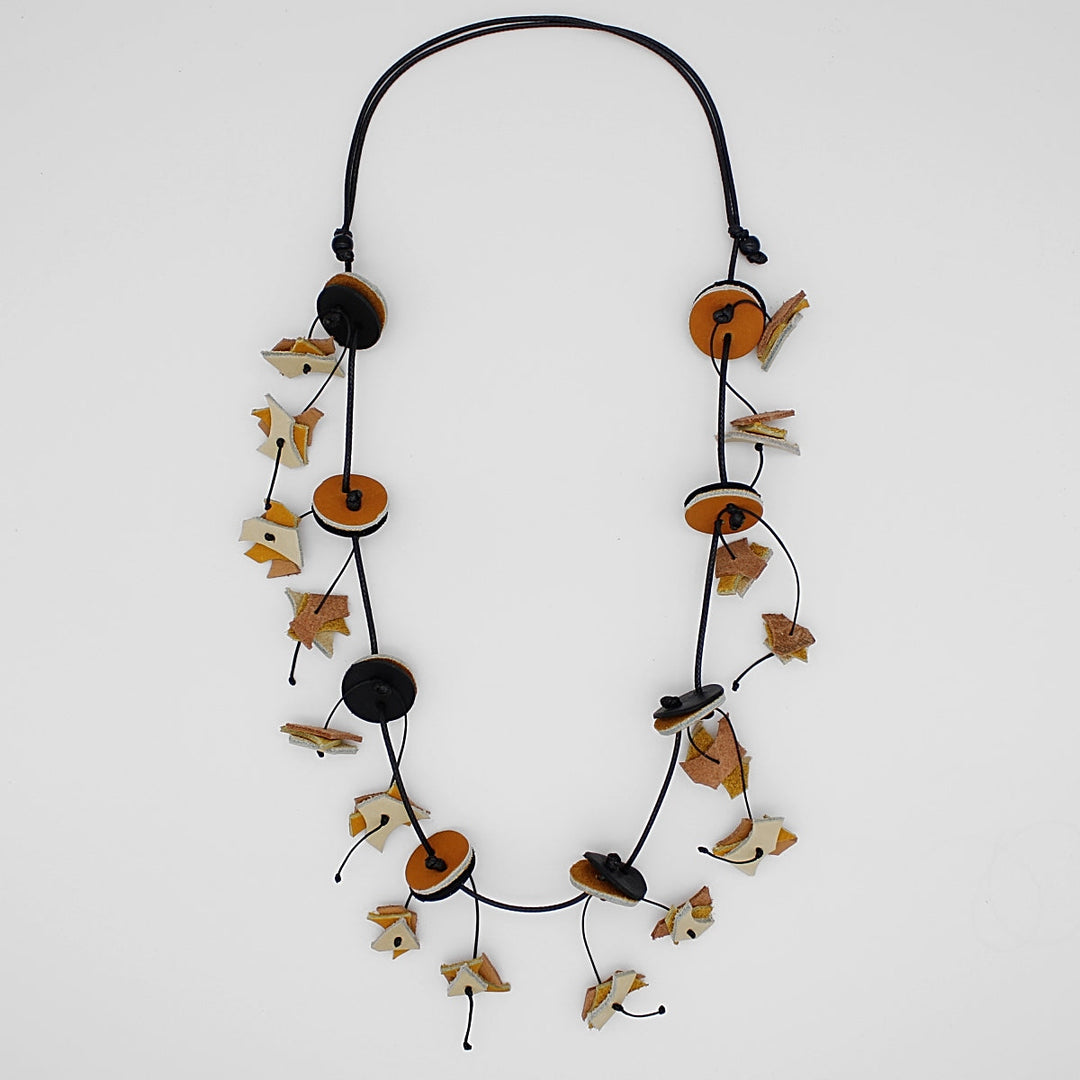 Long beaded necklace with circular discs and decorative leaf-like elements on adjustable cord