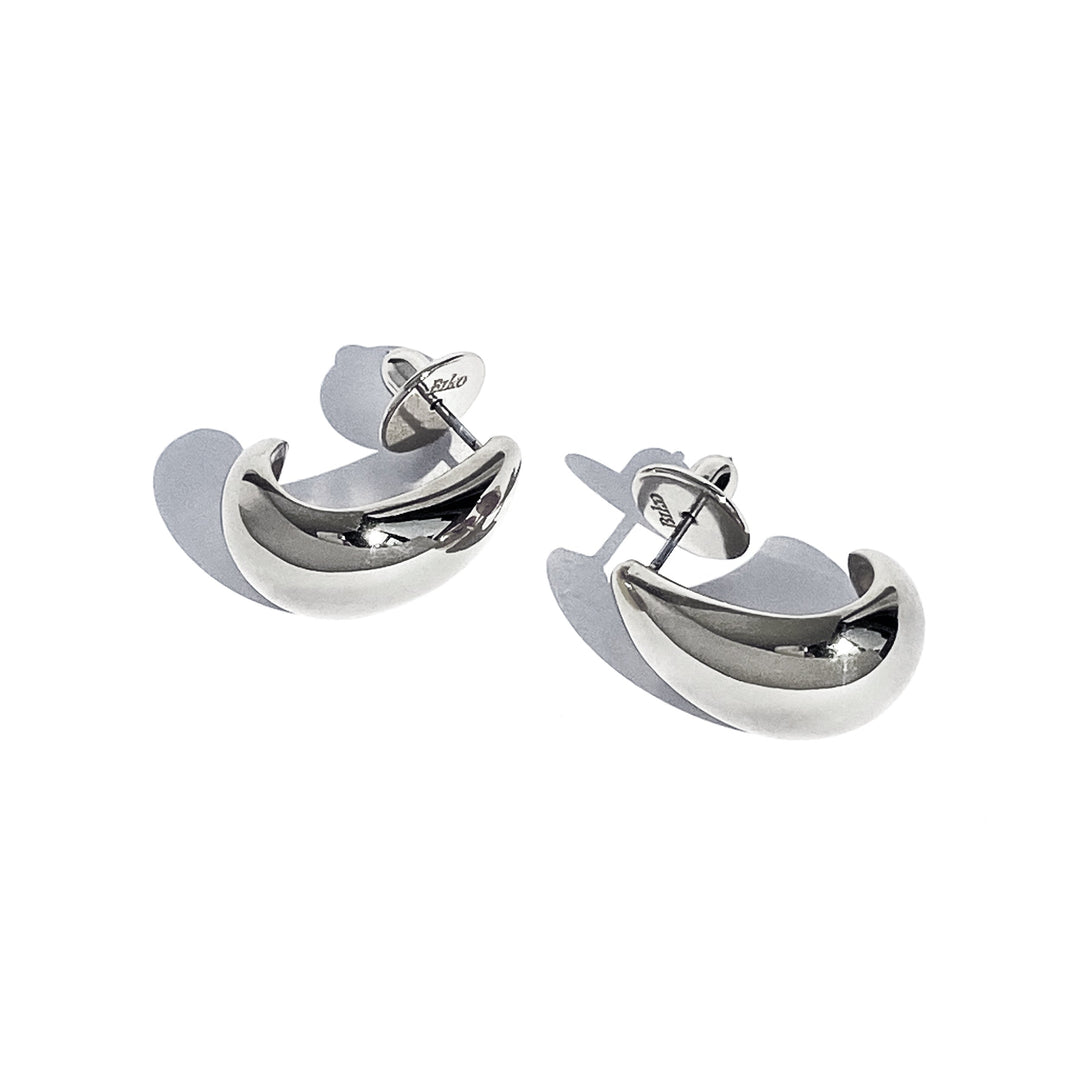 Pair of small curved hoop earrings in polished silver metal on white background