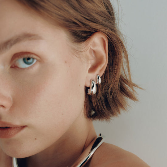 Small silver hoop earrings worn on model, chunky rounded design visible from side angle