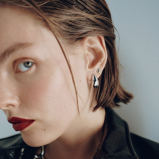Small silver hoop earrings worn by model with short brown hair and red lipstick