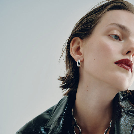 Small silver hoop earring worn on model's ear, profile view showing smooth polished finish