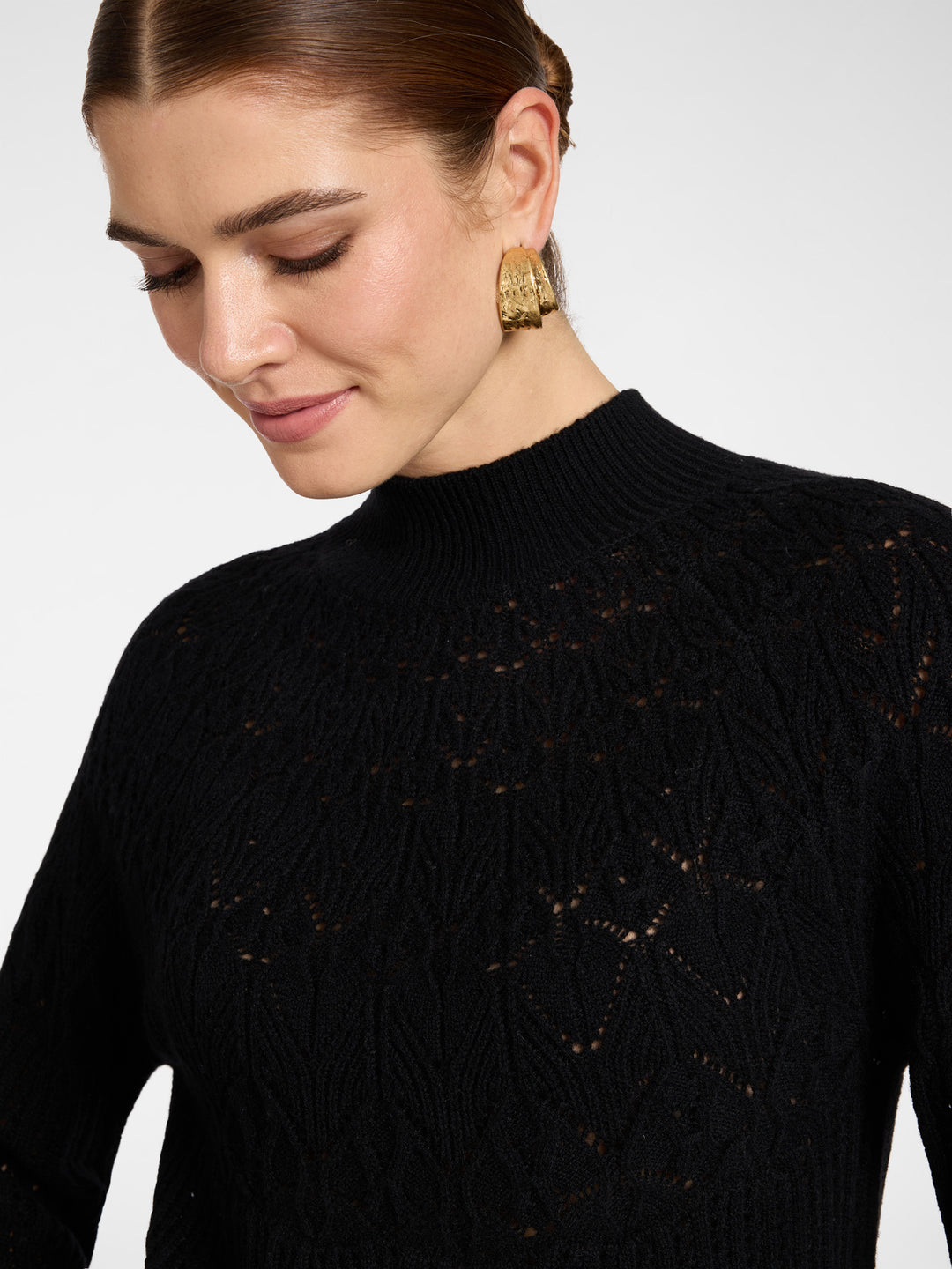 Black wool rib knit pullover close-up with perforated geometric texture, mock neck
