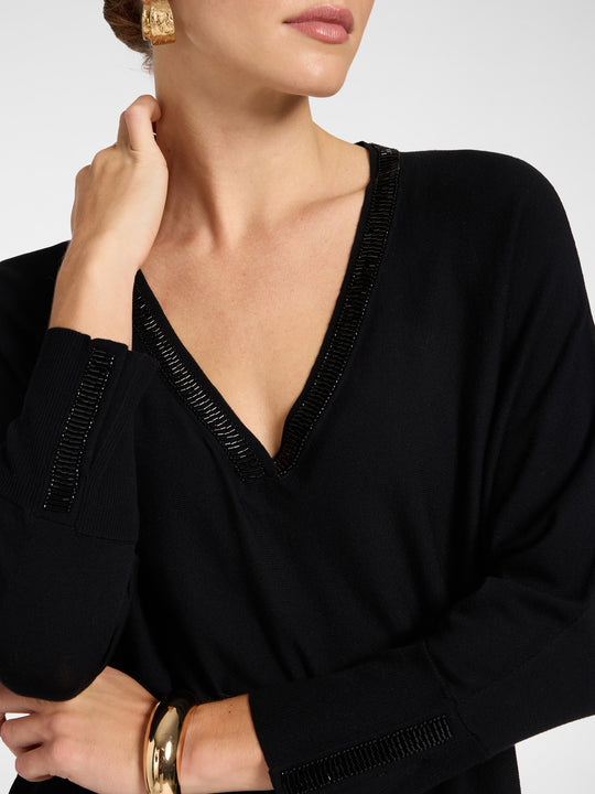 Black V-neck tunic close-up with embroidered trim along neckline and cuffs