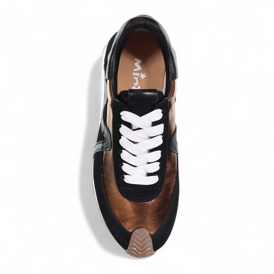 Top-down view of a chunky sneaker with bronze metallic panels, black suede trim, and white laces