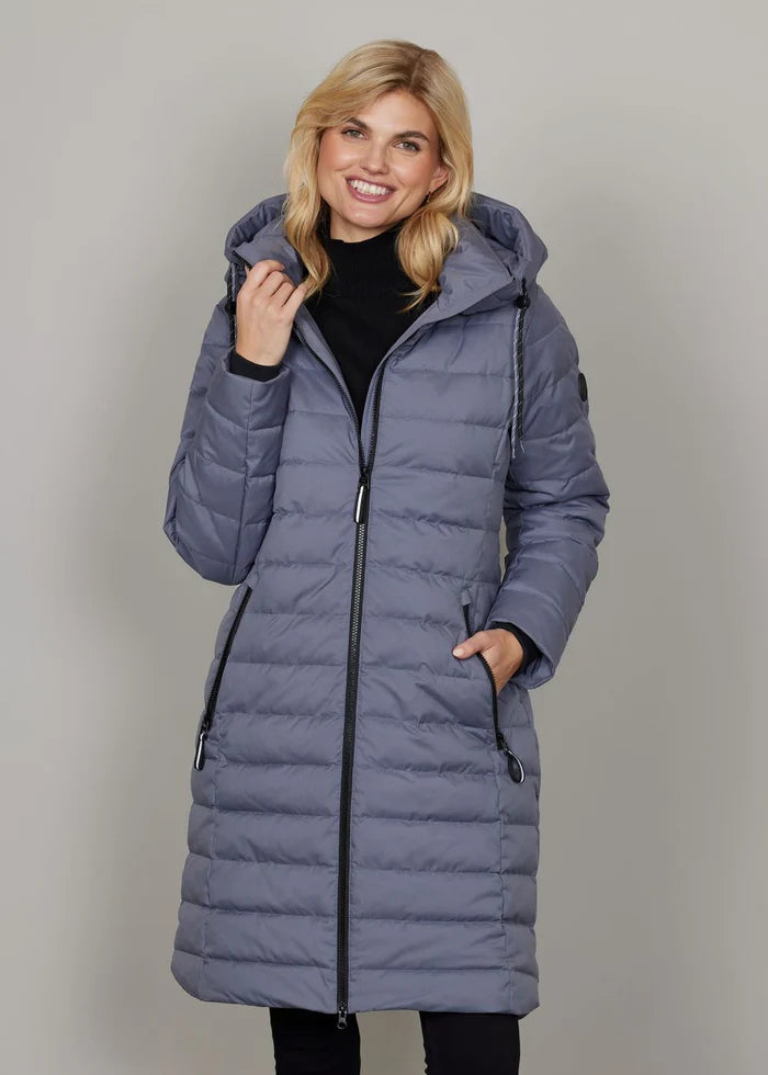 Woman wearing a long blue puffer coat against a plain background