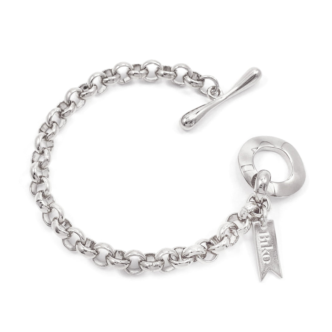 Chain link bracelet with toggle clasp and small banner charm on white background