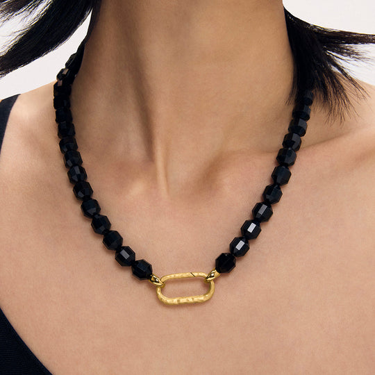 Black faceted beaded necklace with gold oval carabiner pendant clasp worn on model
