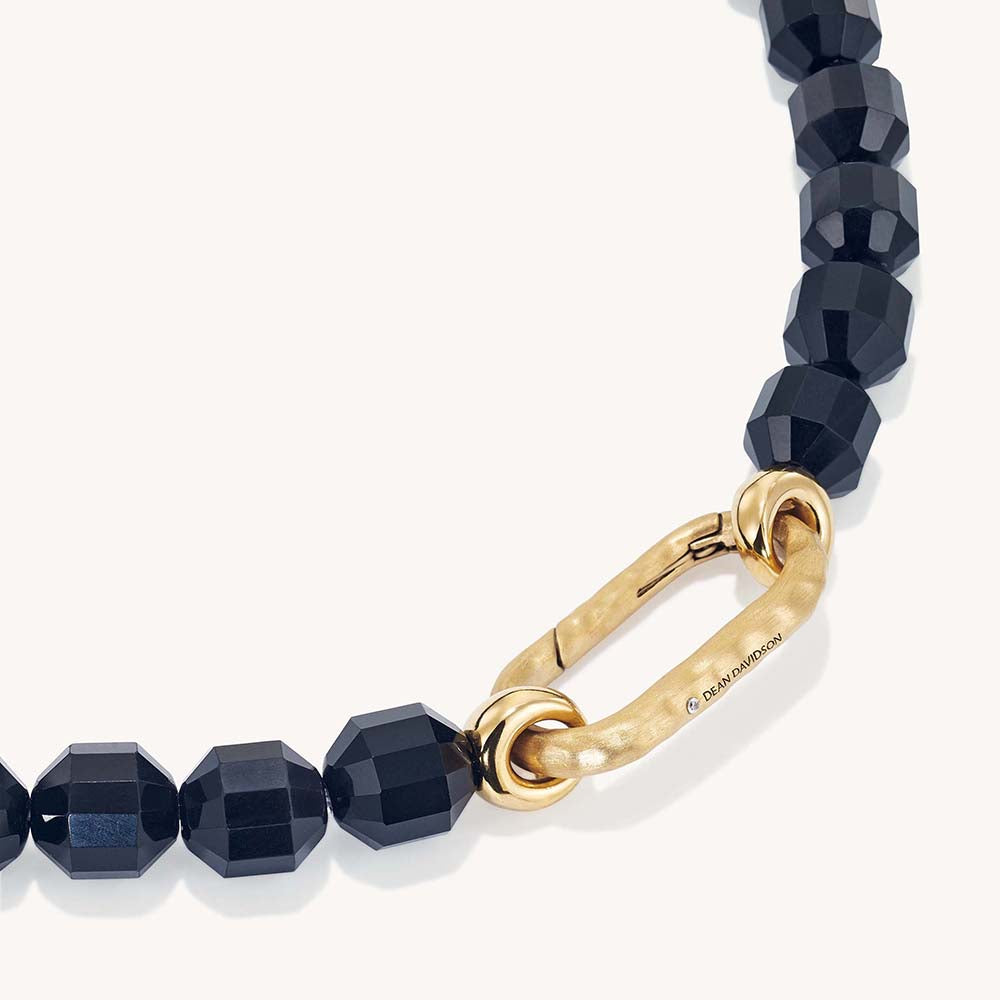 Faceted black beaded necklace with gold oval carabiner clasp, close-up detail view