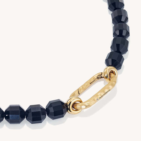 Faceted black beaded necklace with gold oval carabiner clasp, close-up detail view