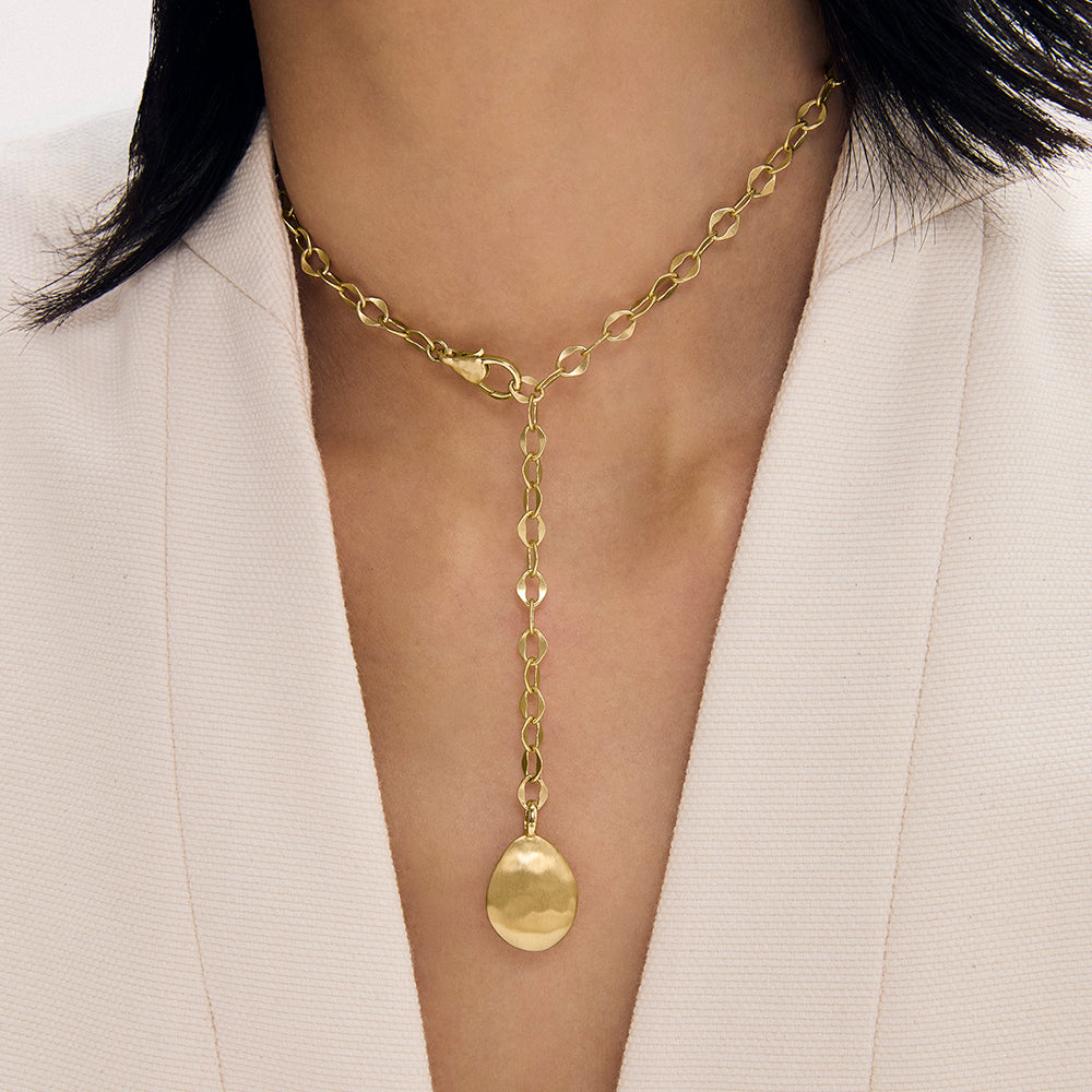 Gold lariat necklace with oval link chain and dome pendant, worn on model