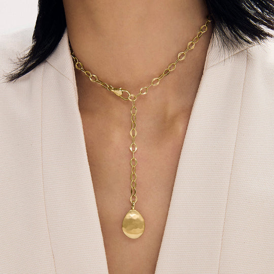 Gold lariat necklace with oval link chain and dome pendant, worn on model