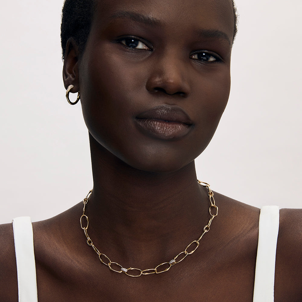 Gold oval link chain necklace with diamond-pavé connectors worn on model's neck