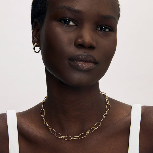 Gold oval link chain necklace with diamond-pavé connectors worn on model's neck
