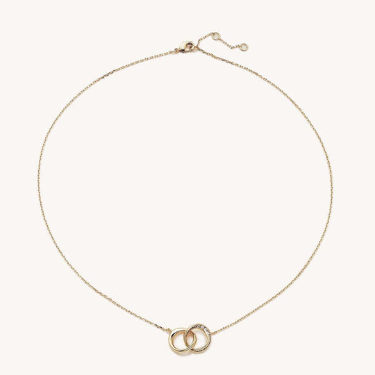 Gold necklace with two interlocking circles pendant, one plain and one pavé white crystal