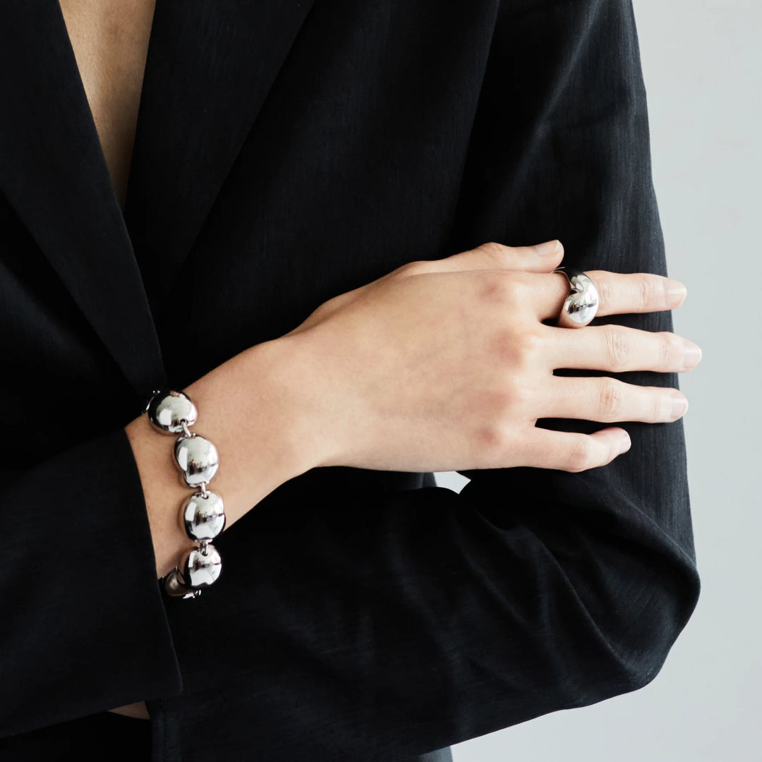 Silver ball-link bracelet on wrist with round bead charms and toggle closure