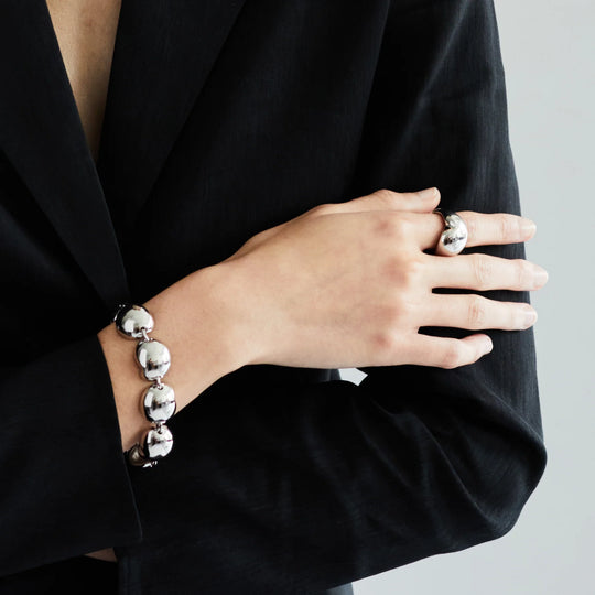Silver ball-link bracelet on wrist with round bead charms and toggle closure