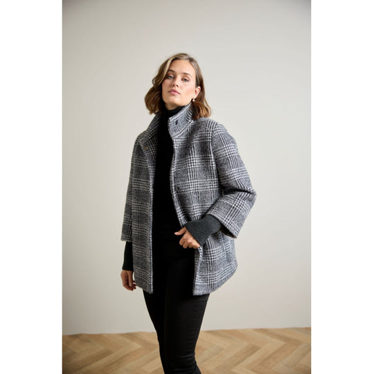 Oversized glen plaid wool coat with ribbed sleeve cuffs and stand collar, three-quarter view on model