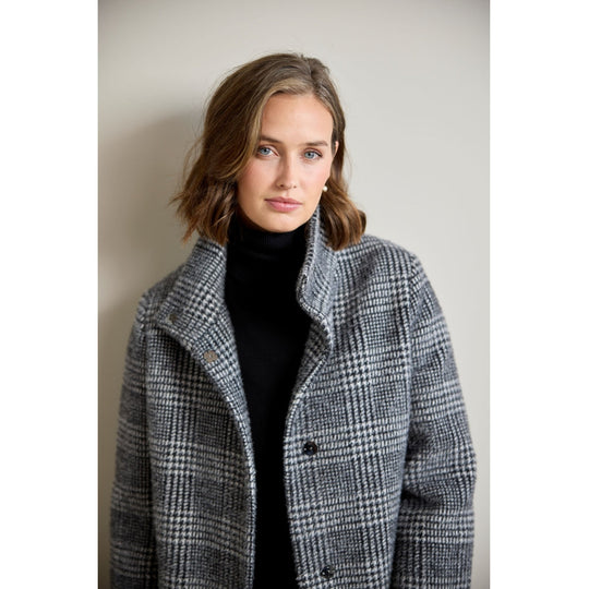 Glen plaid wool coat in black and white check, worn open over black turtleneck, front view