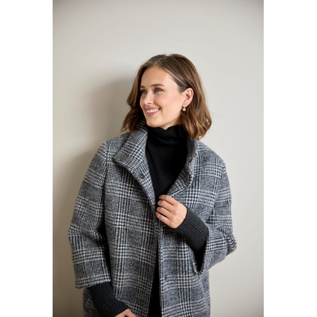 Glen plaid wool coat with ribbed sleeve detail, worn open over black turtleneck, three-quarter view