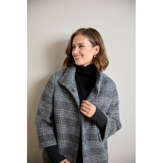 Glen plaid wool coat with ribbed sleeve detail, worn open over black turtleneck, three-quarter view