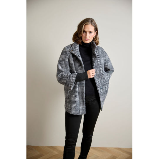 Oversized glen plaid wool coat with ribbed cuffs, worn open over black turtleneck and trousers, front view