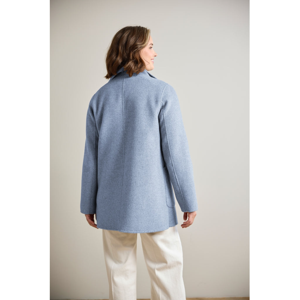 Light blue wool coat with patch pocket, shown from back on model wearing white trousers