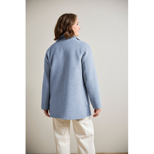 Light blue wool coat with patch pocket, shown from back on model wearing white trousers