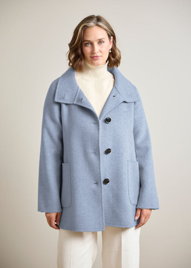 Light blue wool coat with three dark buttons and patch pockets, front view on model