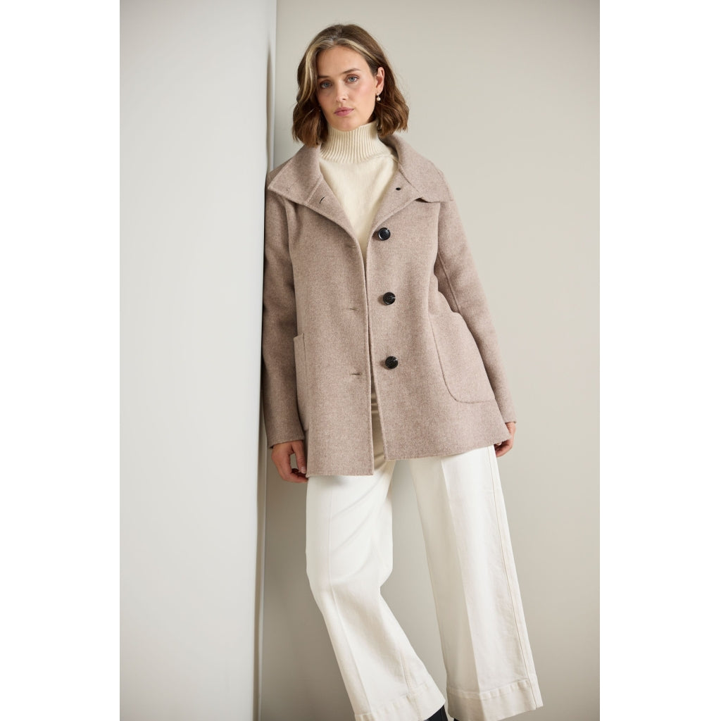 Taupe wool coat with dark buttons, patch pockets, and wide lapels, front view on model
