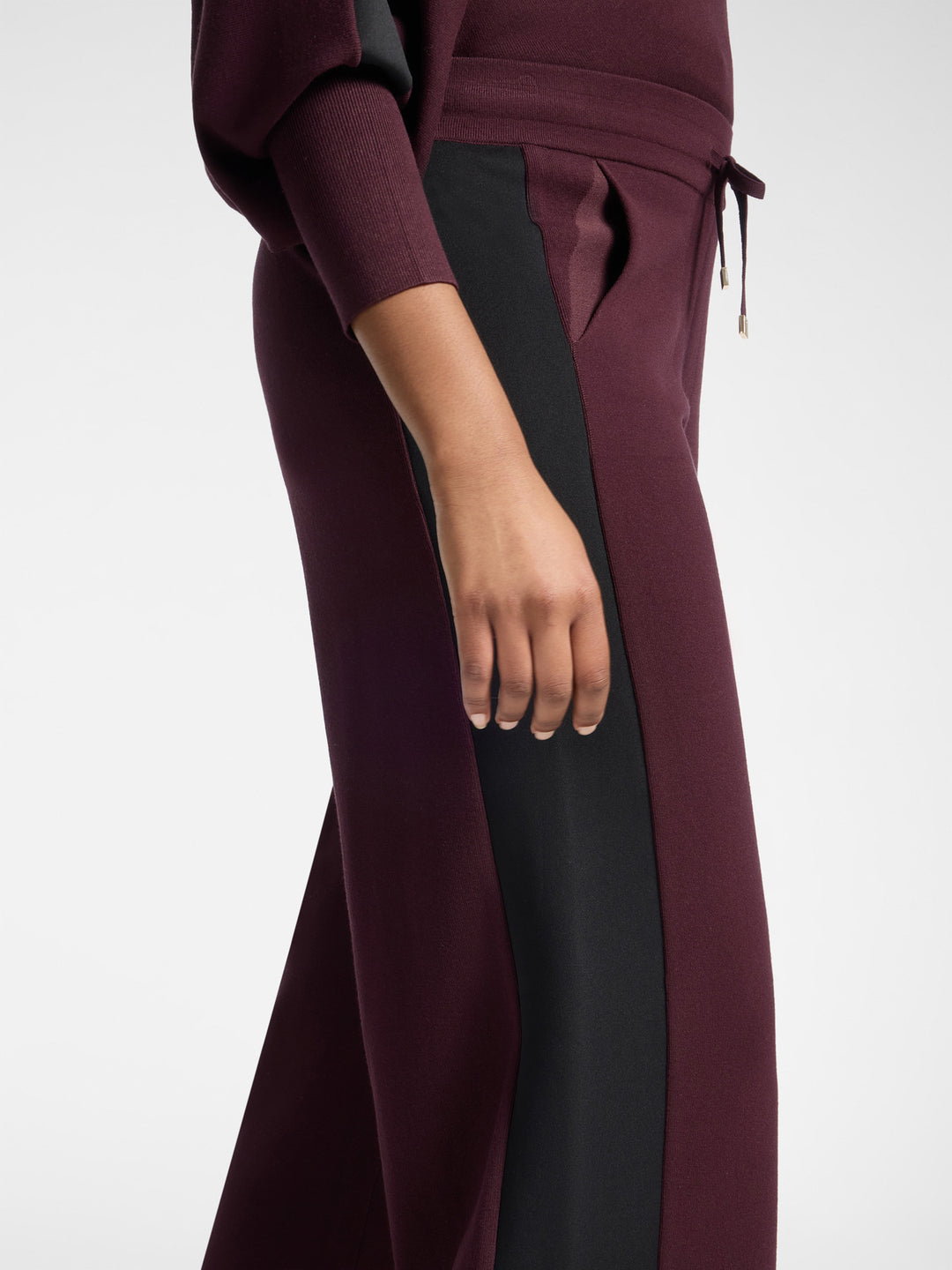Women's viscose athletic trousers with black contrasting insert panel on dark plum legs.