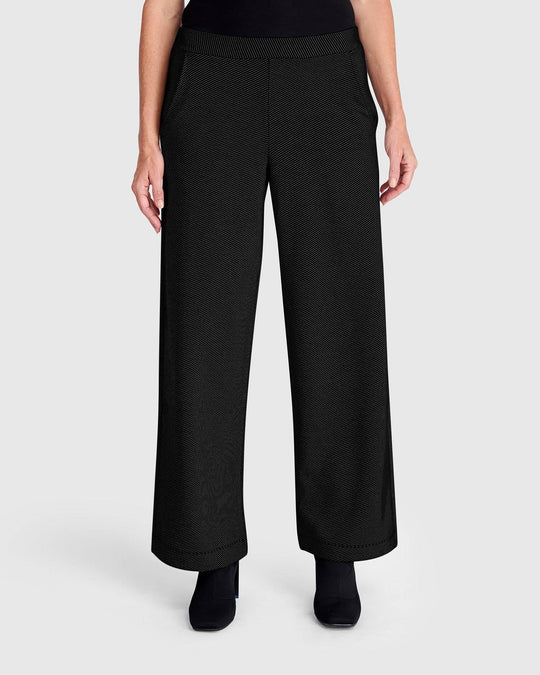 Wide-leg black pull-on pants with subtle texture, worn with black boots, front view