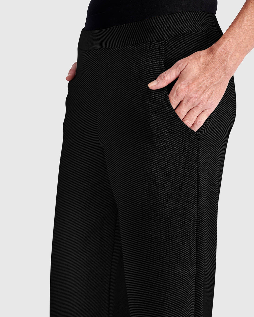 Close-up of wide-leg pull-on pants with ribbed texture, elastic waistband, and side pocket with hand inserted