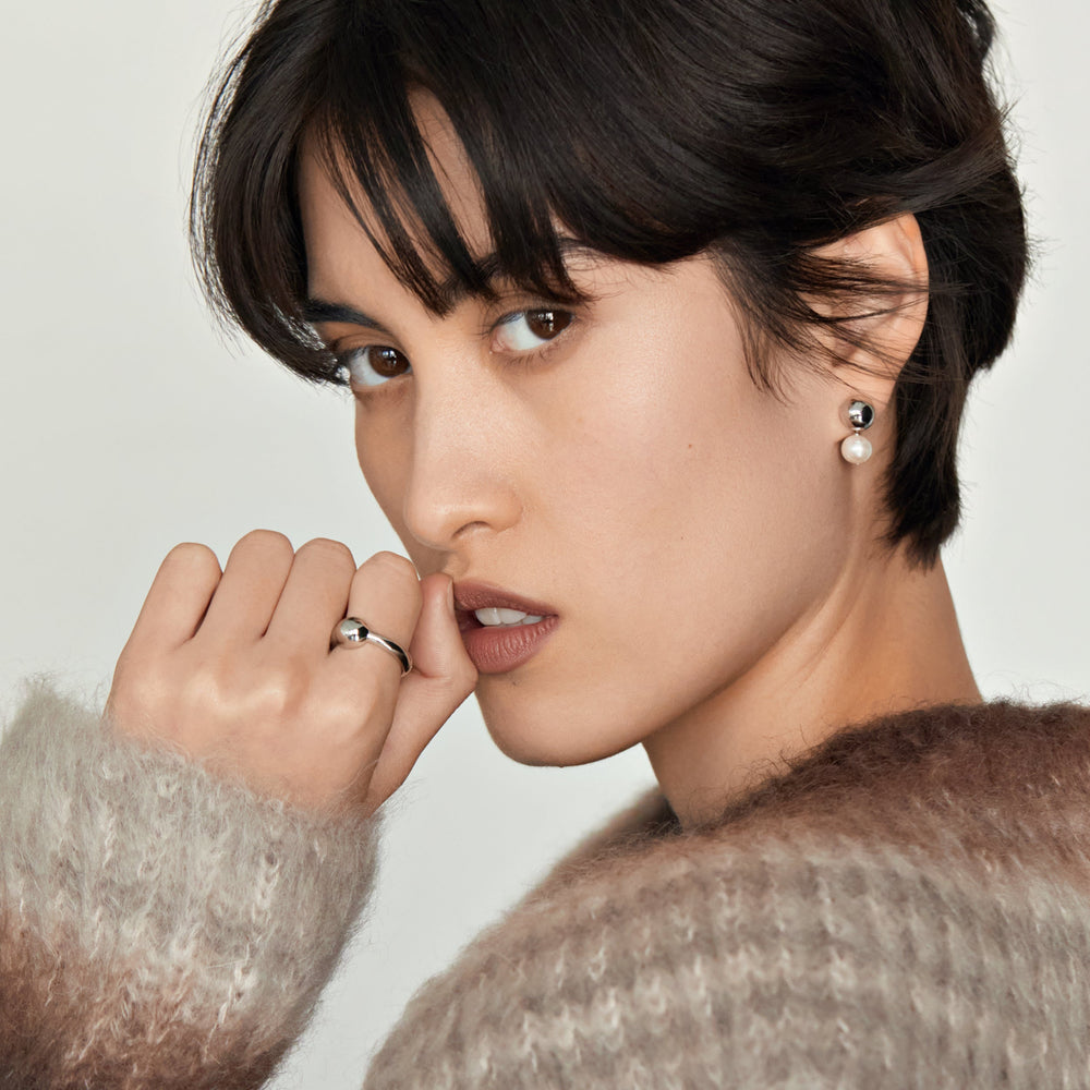 Pearl and silver stud earrings worn by model with short dark hair