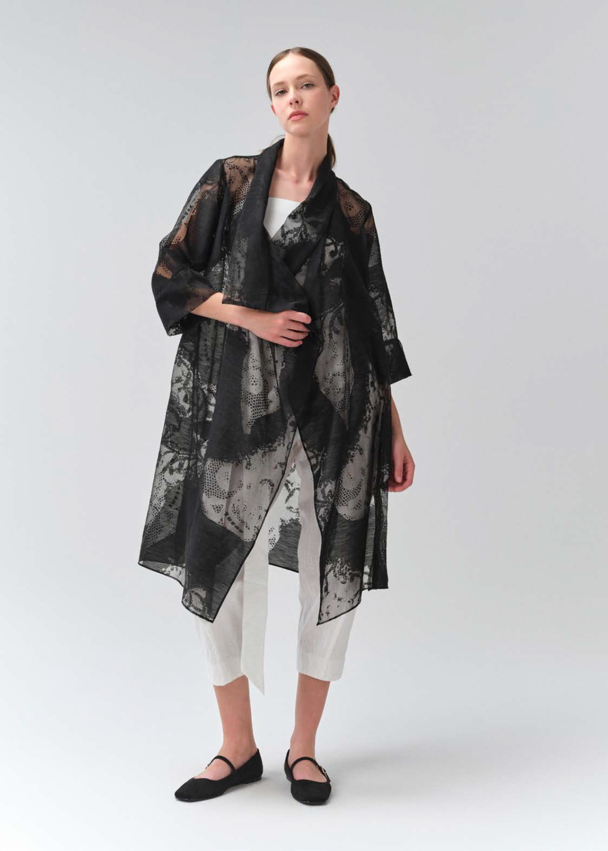 Woman wearing a black and white patterned kimono-style garment on a white background