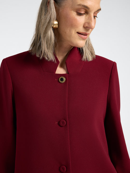 Red stand-collar jacket close-up with three-button placket and decorative trim