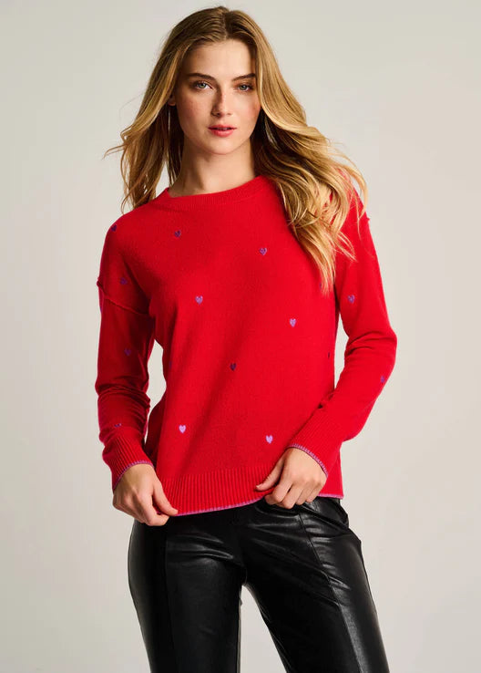 Woman wearing a red sweater with heart patterns against a plain background
