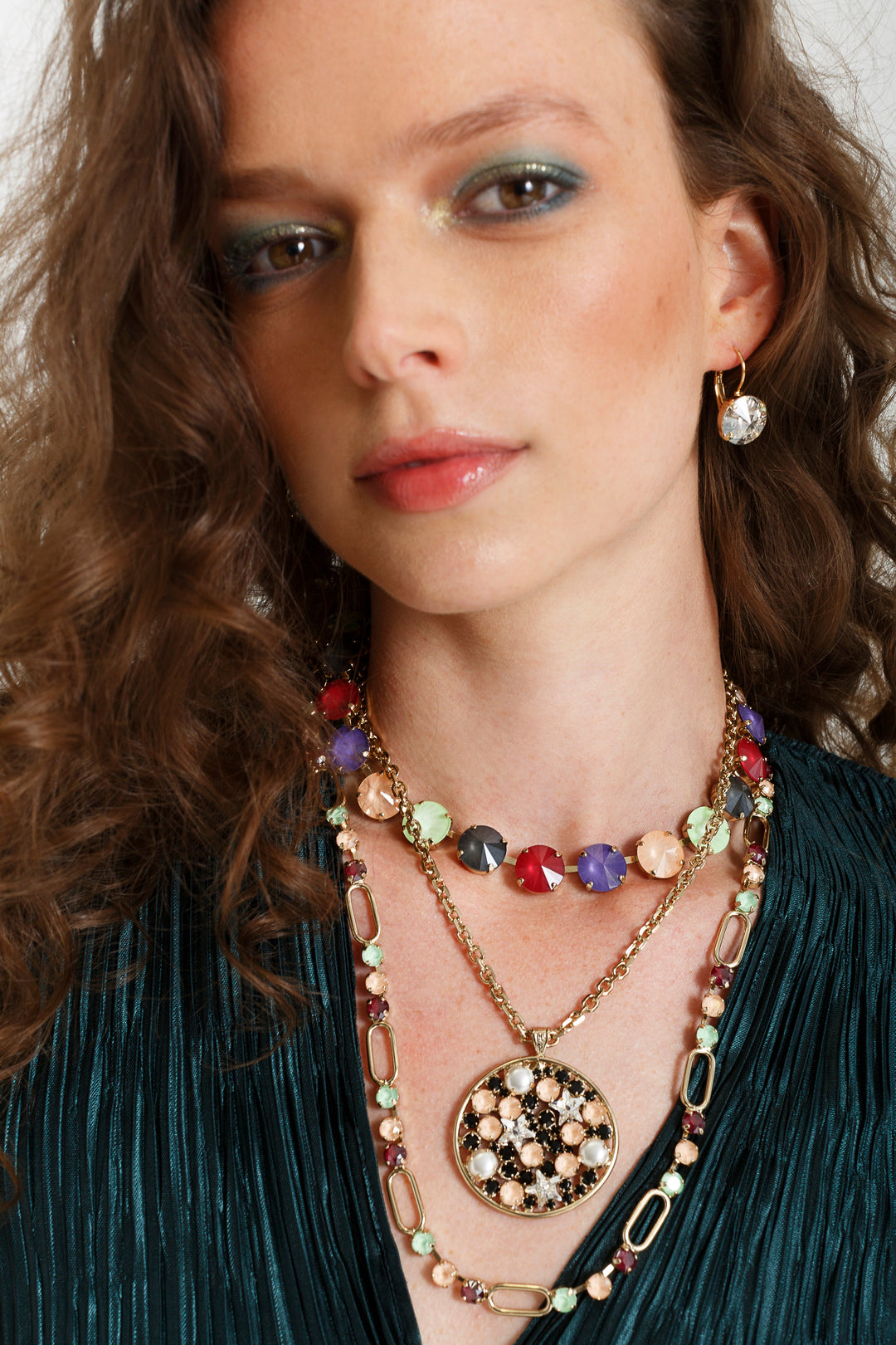Model wearing a single gold drop earring with a clear round rivoli crystal pendant