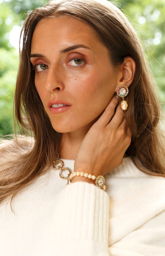 Drop earring with gold-toned crystal cluster top and baroque pearl pendant, worn by model
