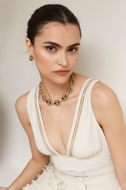 Gold filigree medallion chain necklace with black stones worn by model, with matching earring