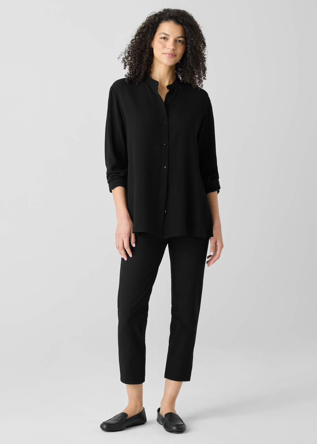 Black slim-fit cropped pants worn with matching black button-up shirt and loafers