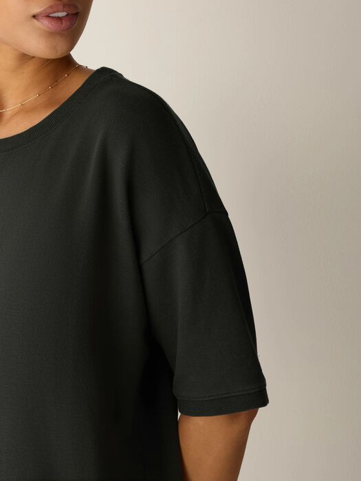 Dark green crew-neck elbow-sleeve dress close-up with side slit seam detail