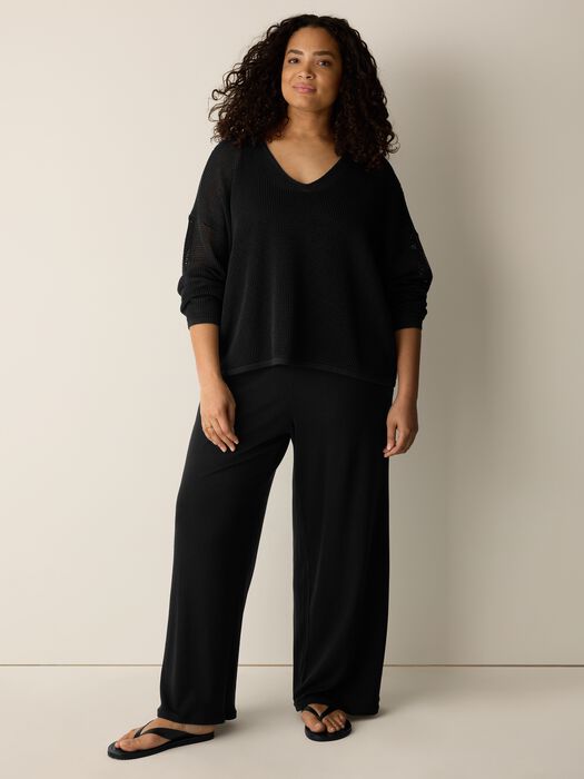 Black open-knit V-neck sweater, draped hem and loose sleeves.